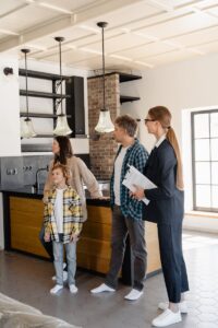 Famille explorant une cuisine de maison moderne avec un agent immobilier, présentant des opportunités d'achat.