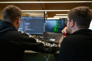 deux hommes assis devant un ordinateur portable