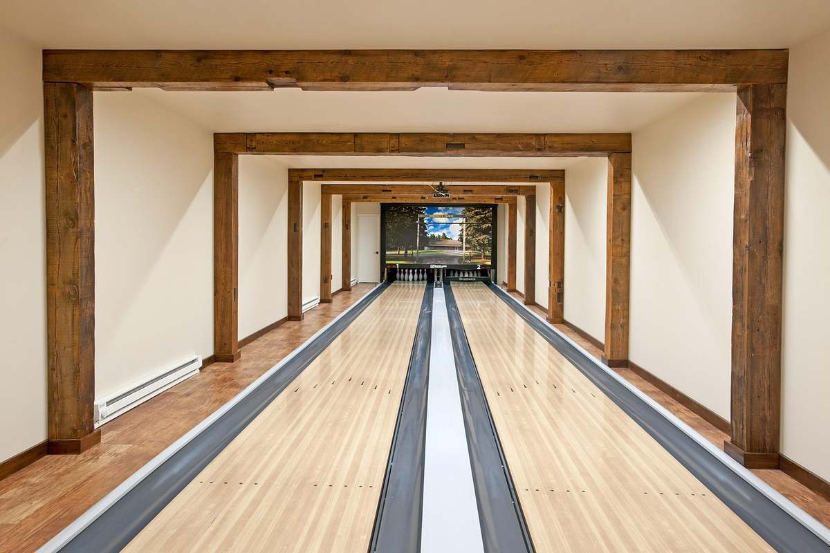 Allée de bowling avec pistes en bois, poutres apparentes et quilles à l'extrémité