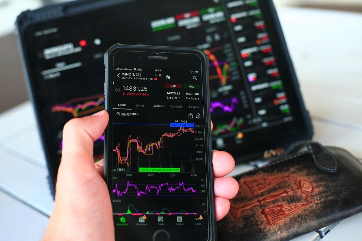 Graphiques financiers sur smartphone et tablette, portefeuille en cuir sur une table Graphiques financiers sur smartphone et tablette, portefeuille en cuir sur une table
