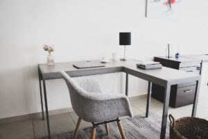Bureau d'angle, chaise, lampe, vase, ordinateur, tapis, panier